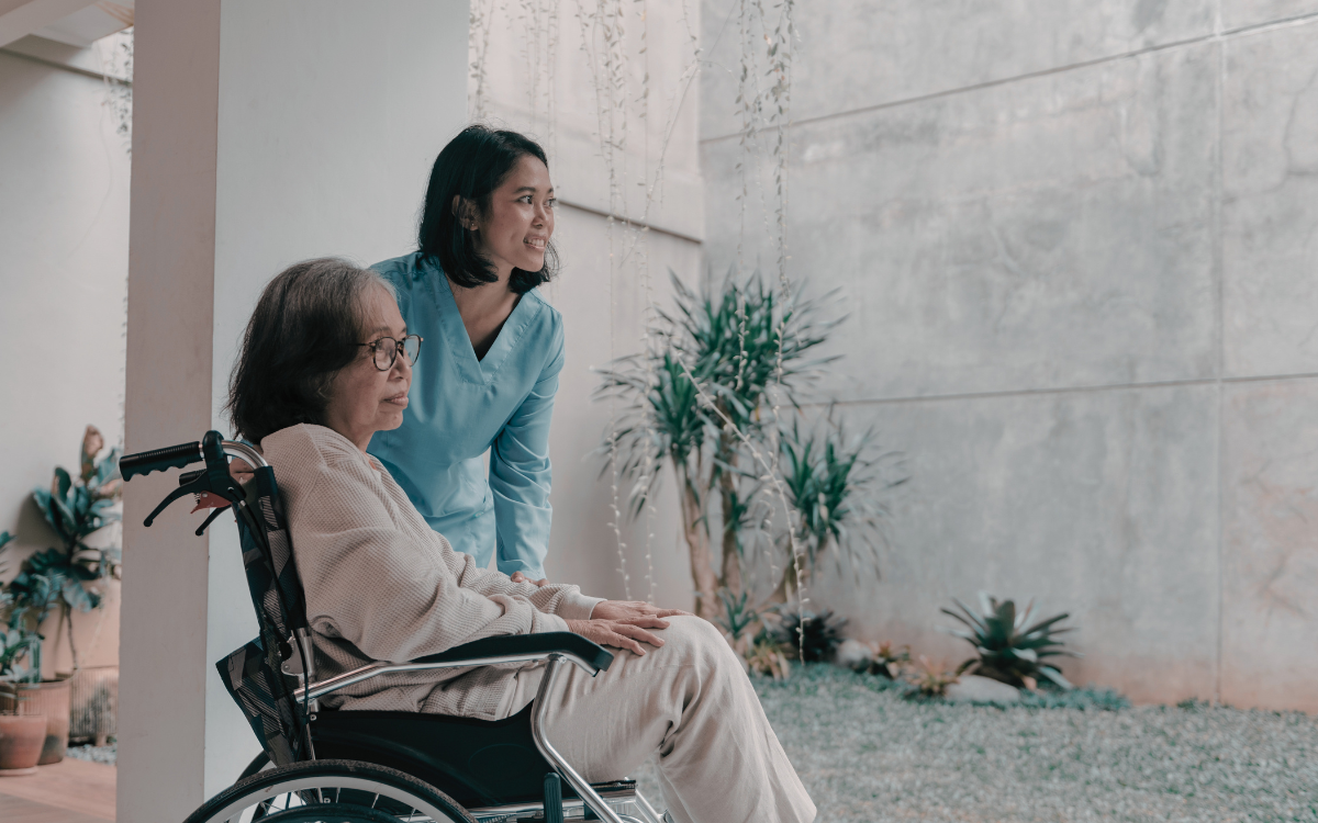 A woman in a wheelchair and her carer looking into the distance