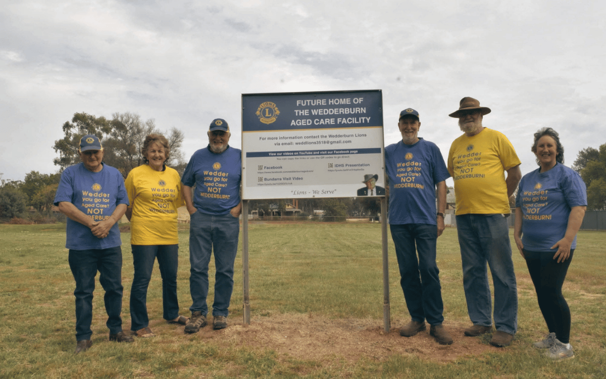 Six members of the Wedderburn Lion's Club standing in front of a sign.